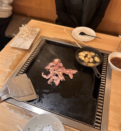 Pork and bean sprouts cooking on the griddle built into the table